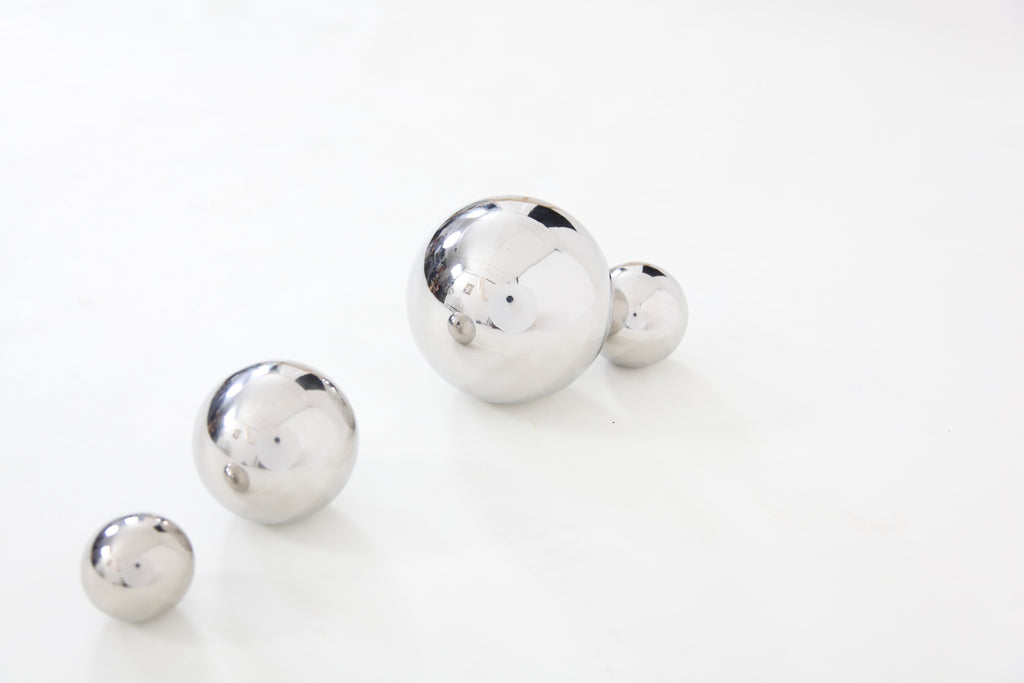 Four shiny silver steel sensory balls on a plain background, staggered by size