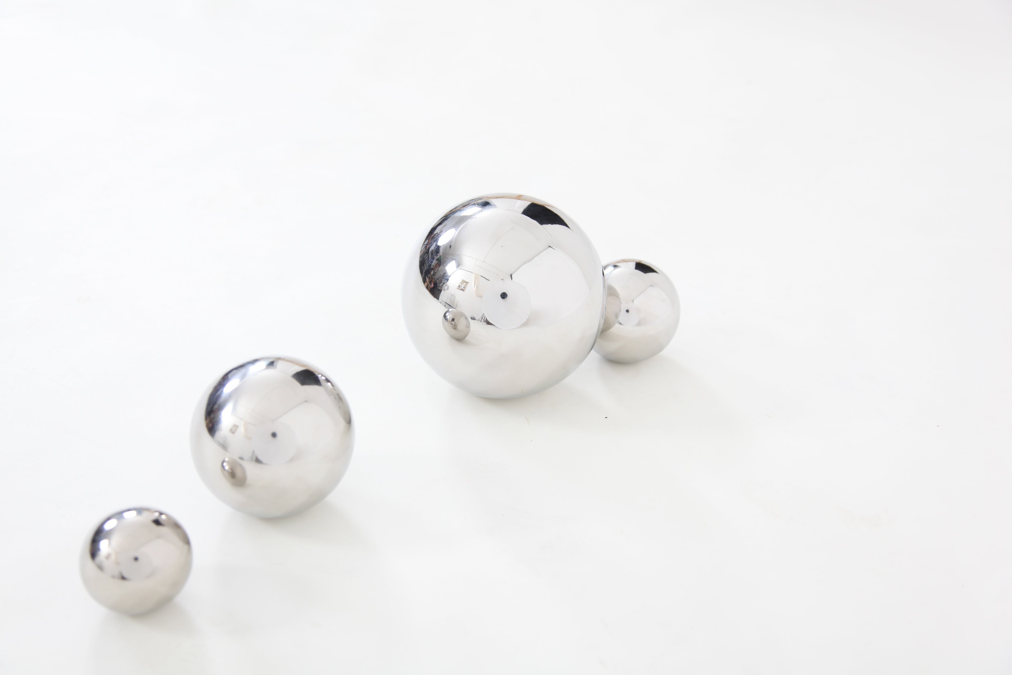 Four shiny silver steel sensory balls on a plain background, staggered by size
