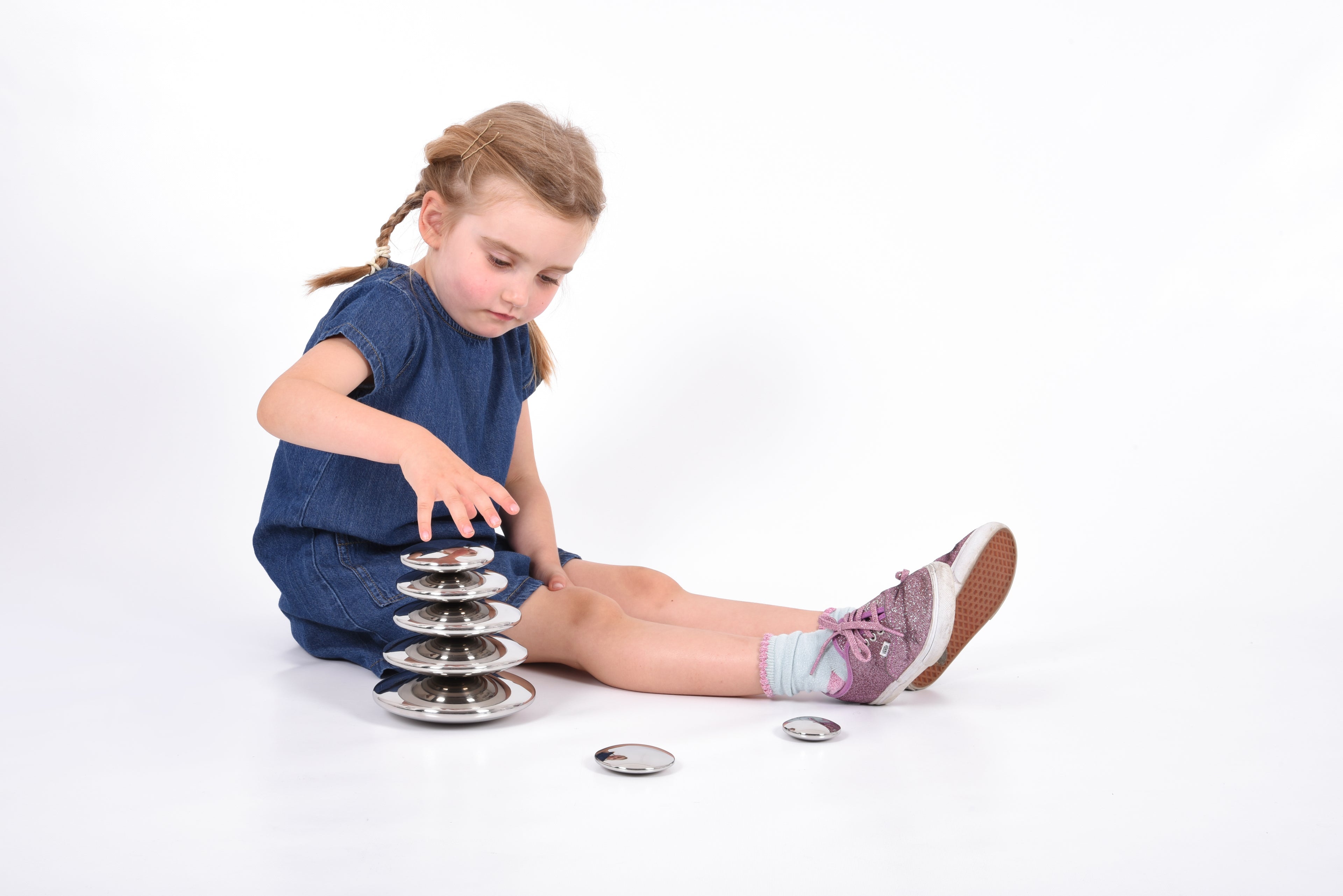 Seven round silver sensory metal buttons scattered beside a tall stacked base