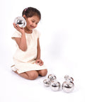Set of 7 shiny silver steel sound balls, held by a child during play