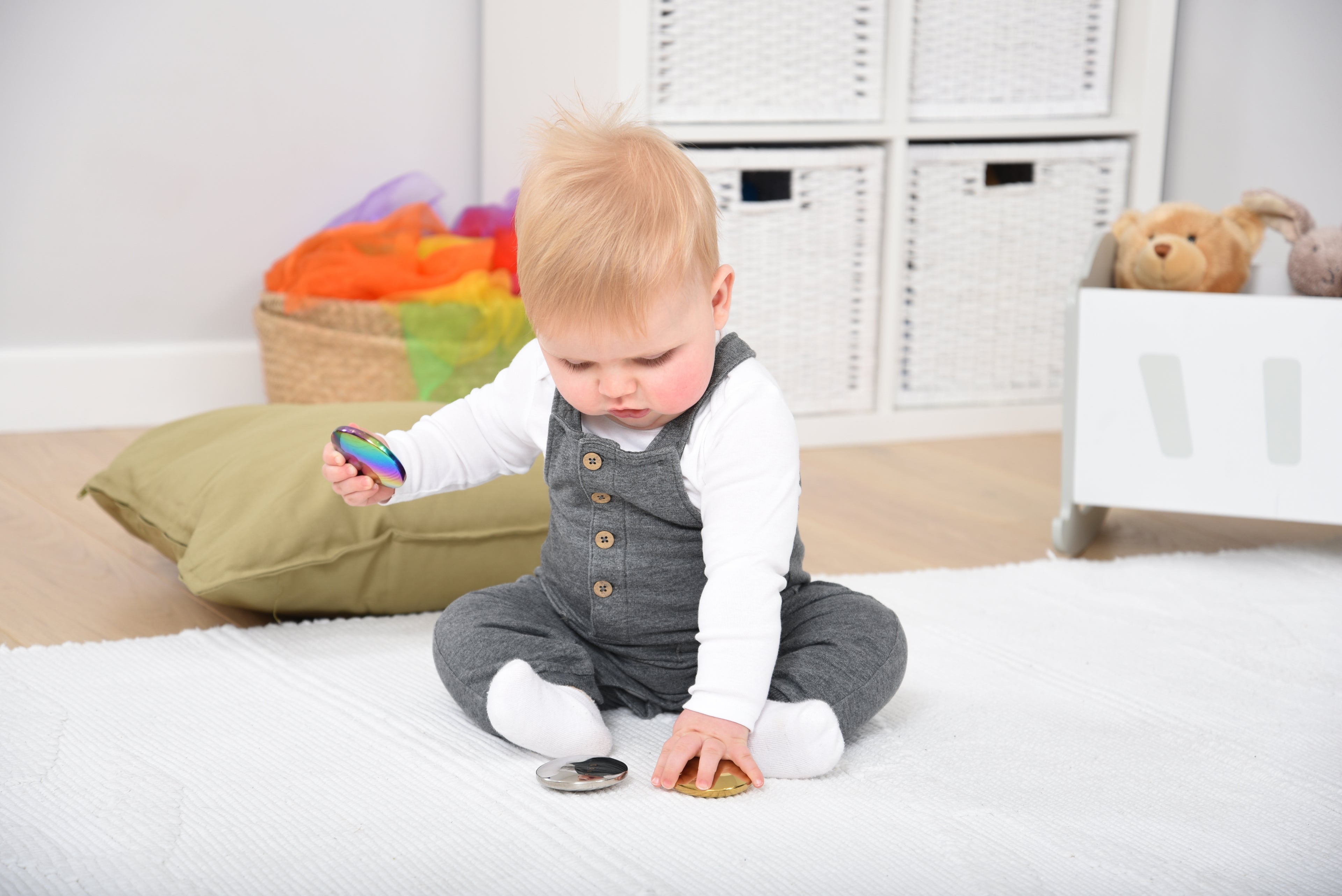 Child reaching for sensory sound buttons, showing colorful iridescent metal cap