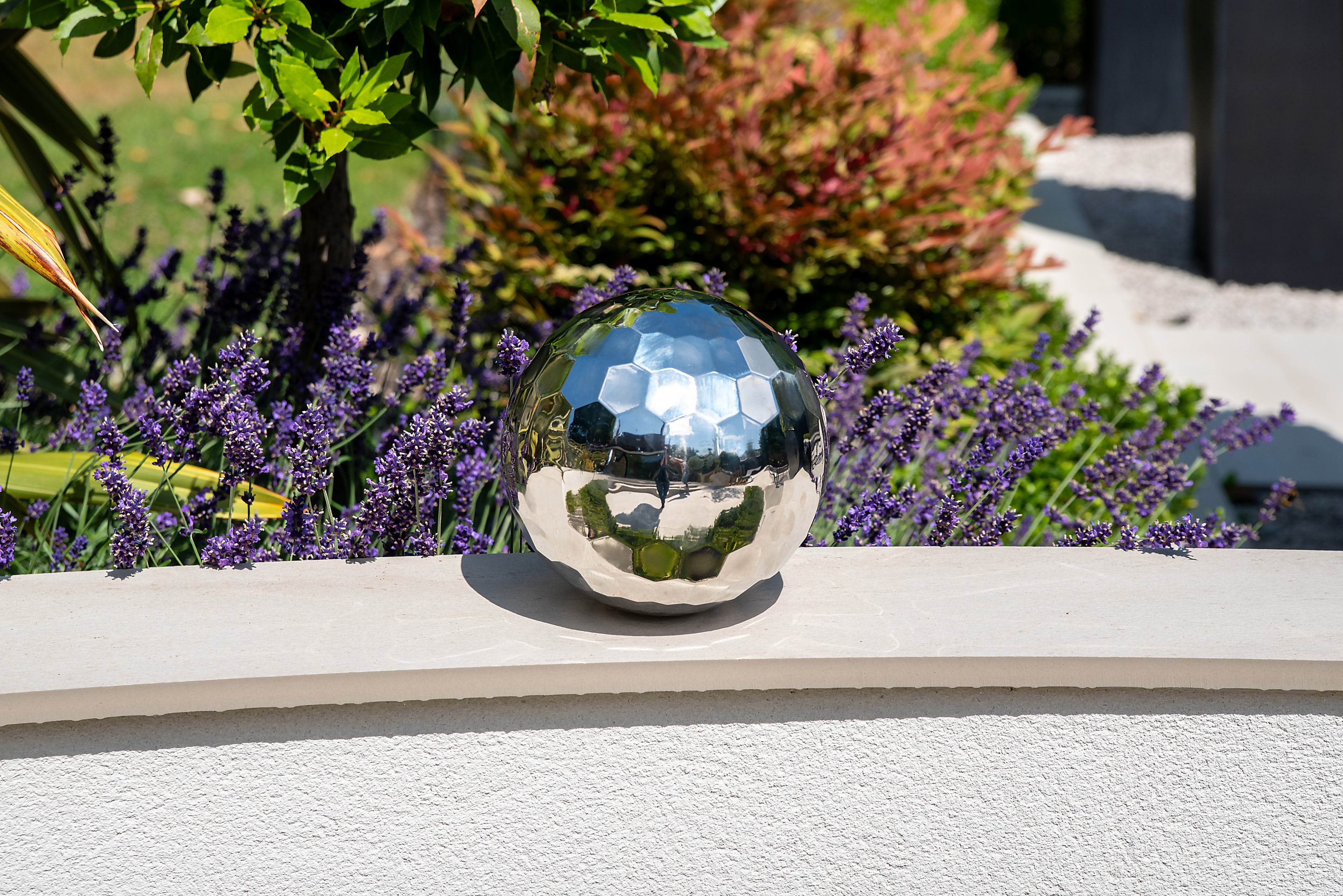 Reflective steel tumble ball with mirrored facets on a patio step
