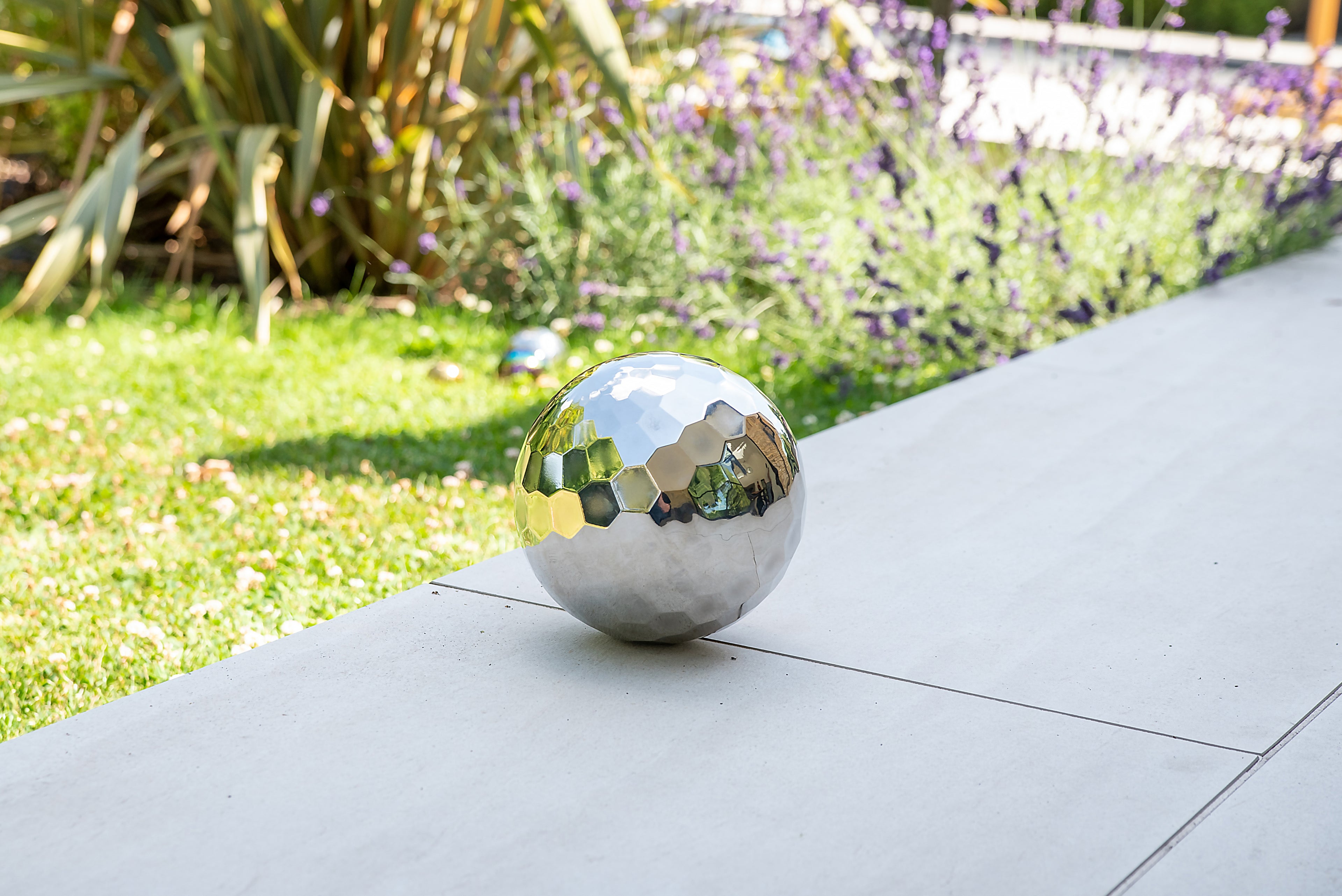 Reflective steel tumble ball, rounded mirrored segments with greenish highlights