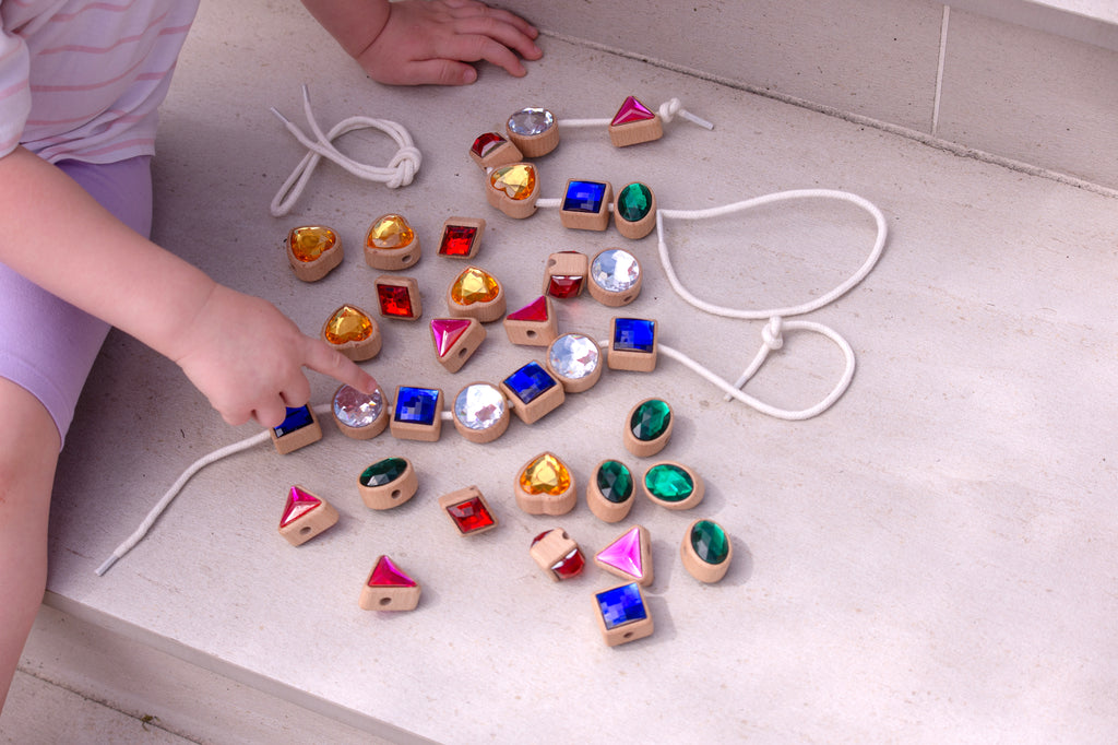 Shape lacing jewels scattered with white cords: blue squares, green ovals, pink triangles, gold hearts