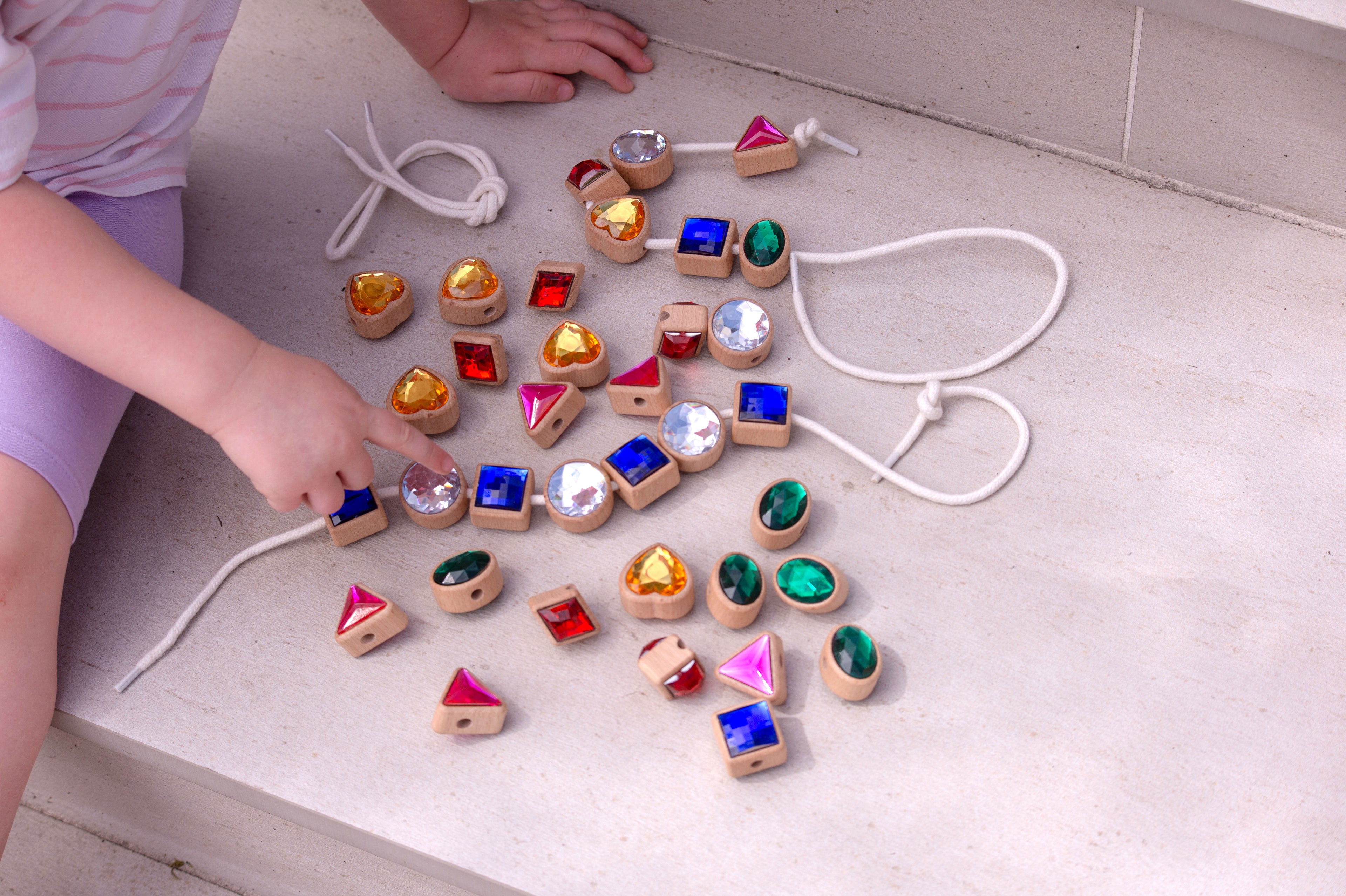 Shape lacing jewels scattered with white cords: blue squares, green ovals, pink triangles, gold hearts