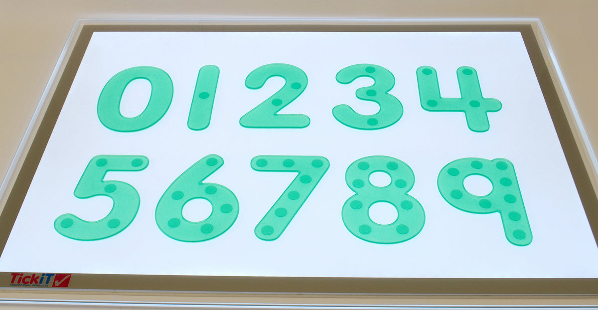 Close-up of green dot number tiles on a white board with digits 0 to 9