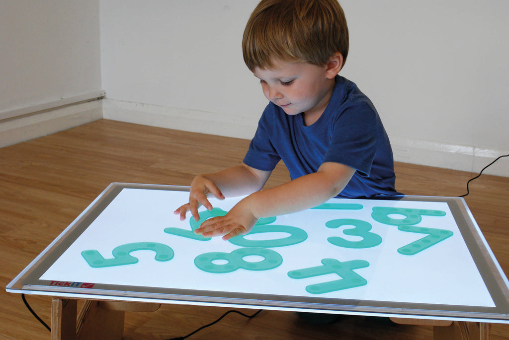 Green dot number tiles on a white board for learning play