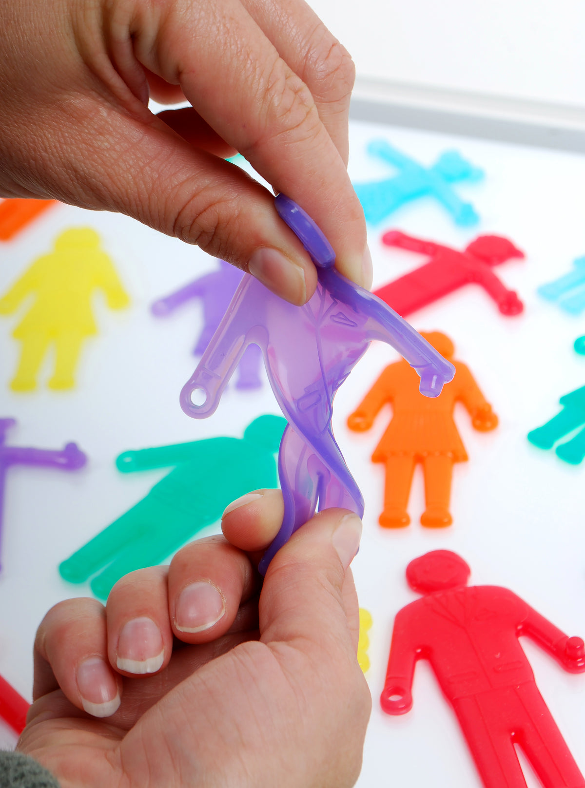 Hands placing a purple plastic people figure onto a board with red and blue figures