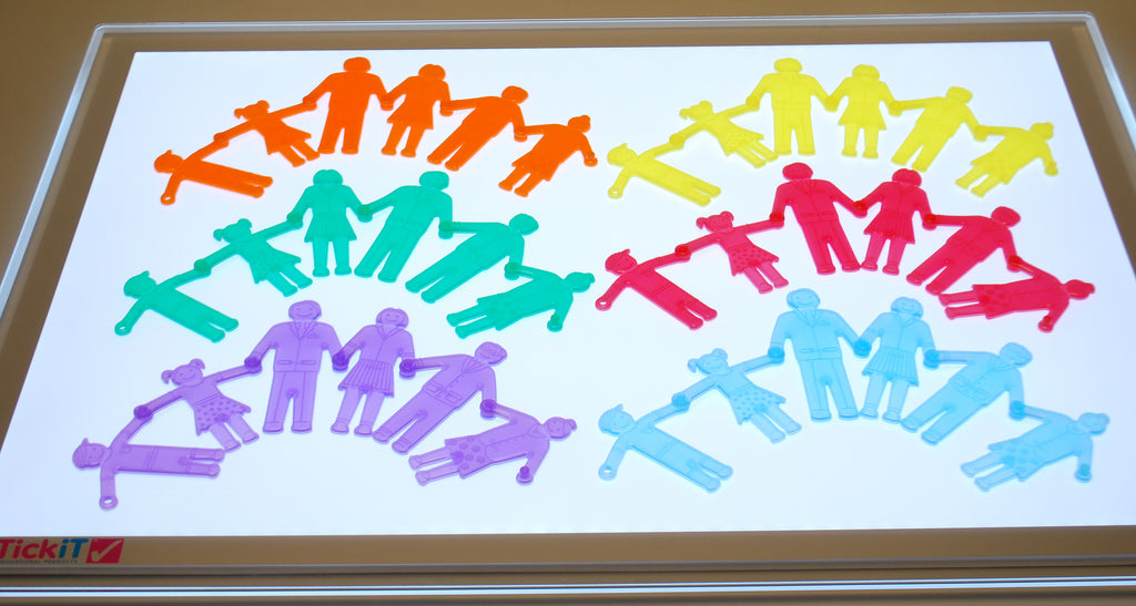 Colorful plastic people toy pieces on a framed clear board, rainbow assortment