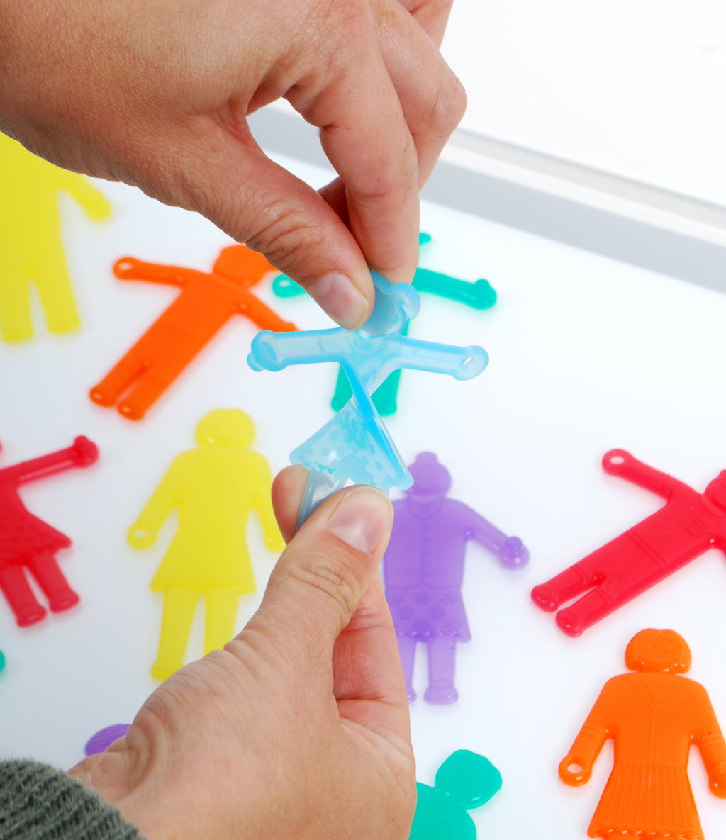 Hands assembling a light blue plastic people figure onto a board with other colors