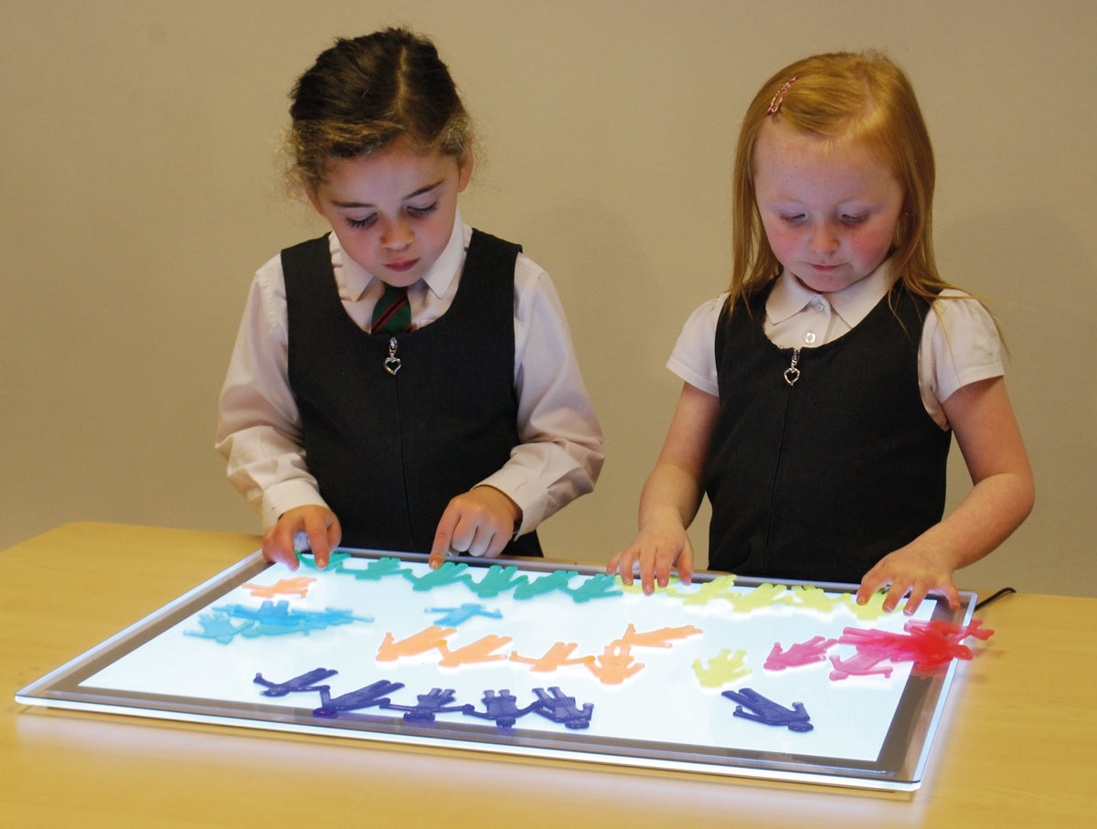 Two young children playing with a large clear activity board of colorful plastic figures