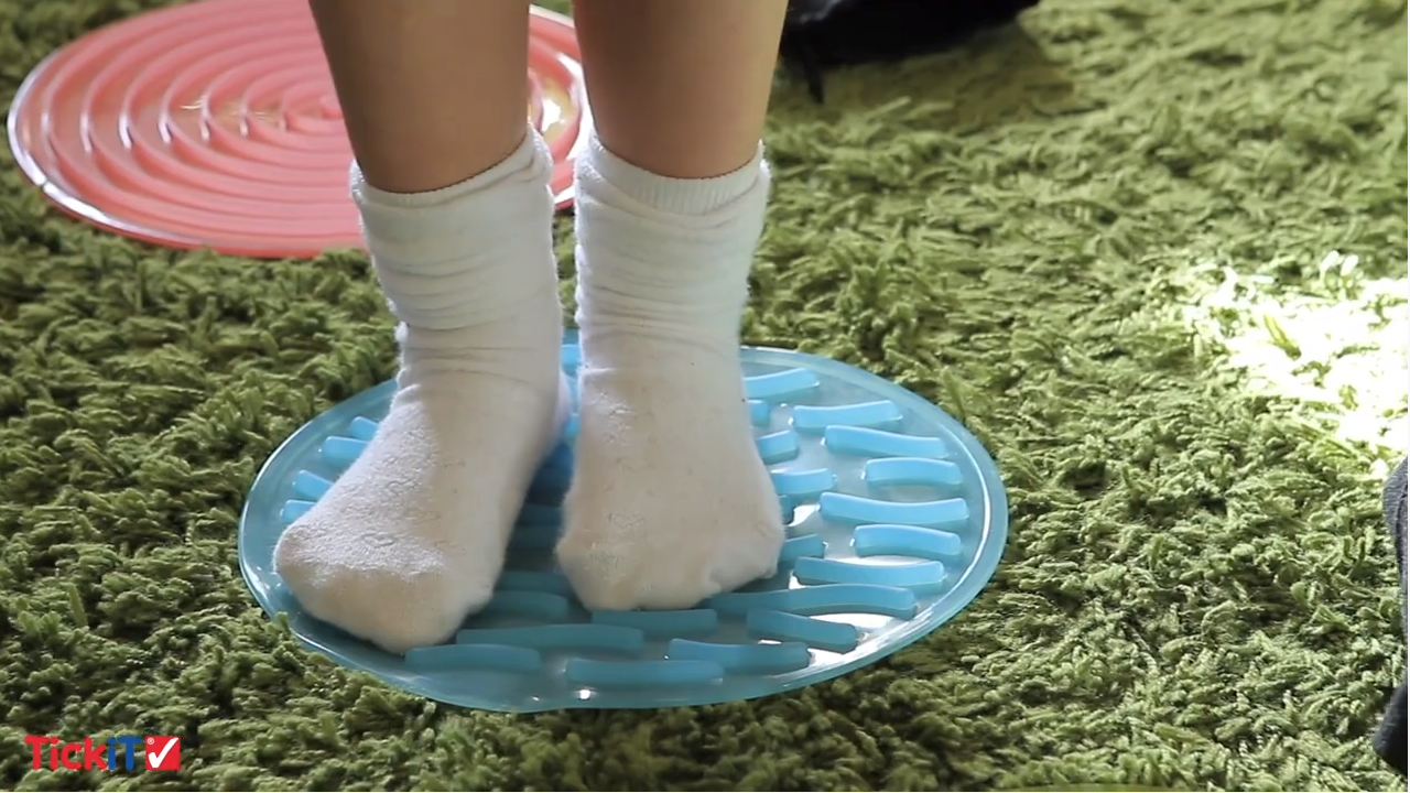 Bare feet on a blue tray of sensory circles in assorted colors