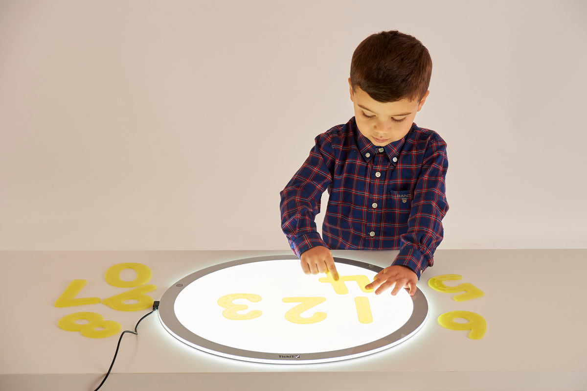 Child reaching to trace yellow number pieces on a circular tracing board