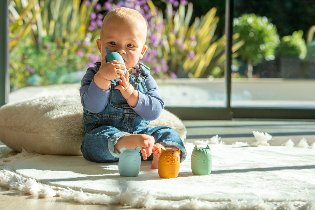 Animal squirter toys on play mat: teal and orange cups with small green squirter