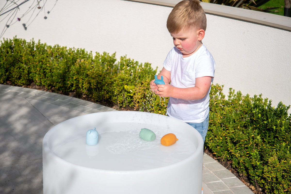 Animal squirter toys in water tub: blue, green, and orange cups
