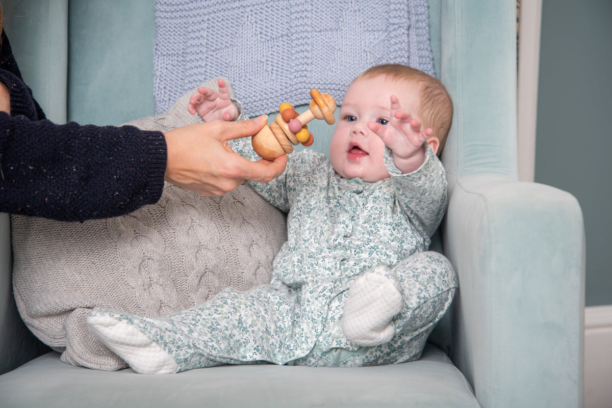 Baby playing with wooden bead rattle with pastel beads