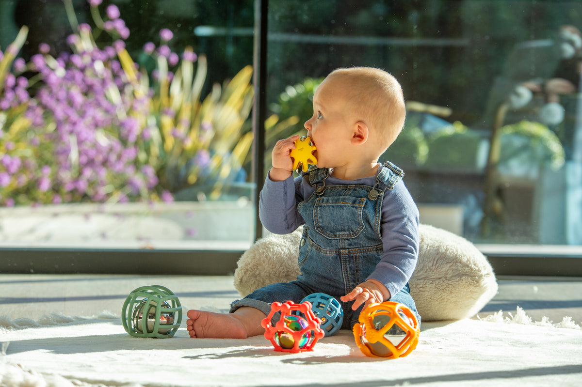 Rainbow flexi ball toy set; baby plays with colorful textured balls on the floor