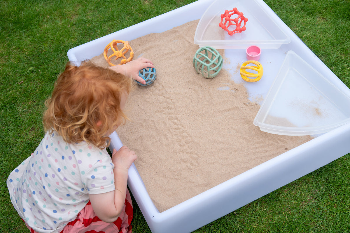 Rainbow flexi ball toy set; toddler plays with colorful textured balls near a sand tray