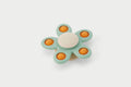 Flower spinner toy with teal petals and orange centers, white hub