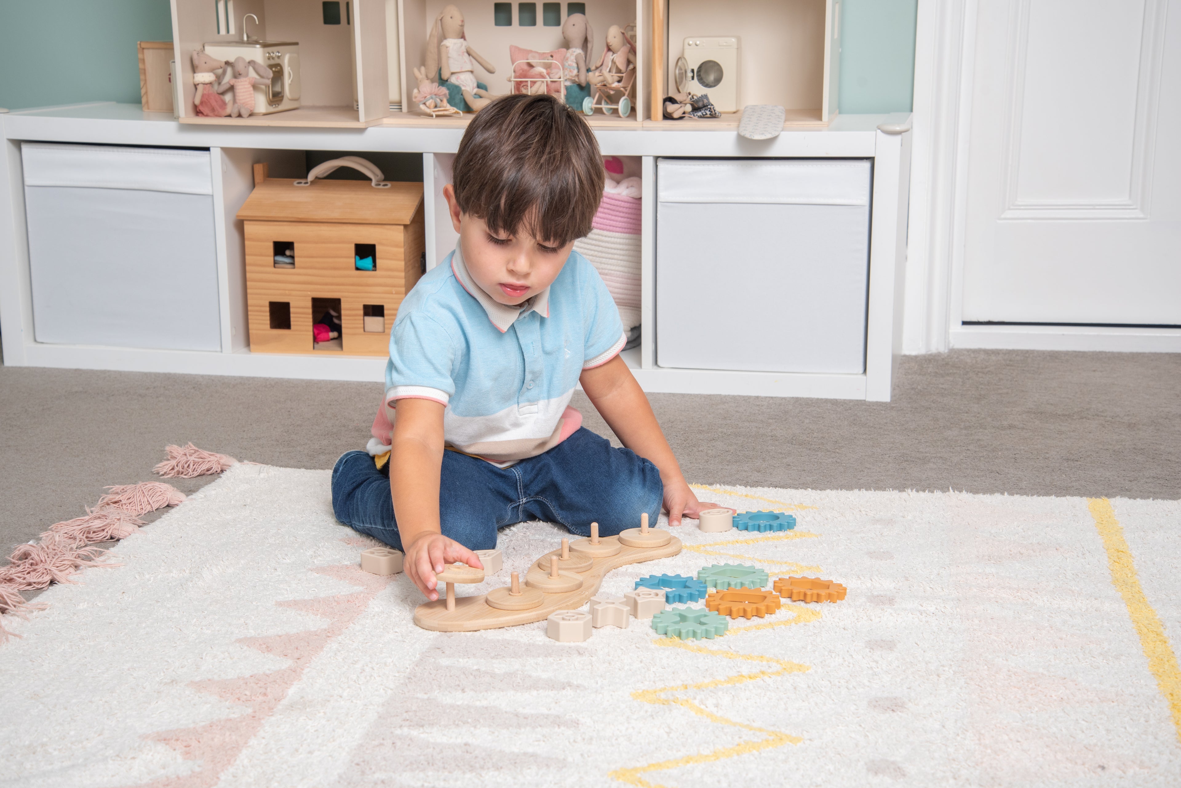 Silisoft Gears puzzle on floor; child uses blue and orange gear pieces on base
