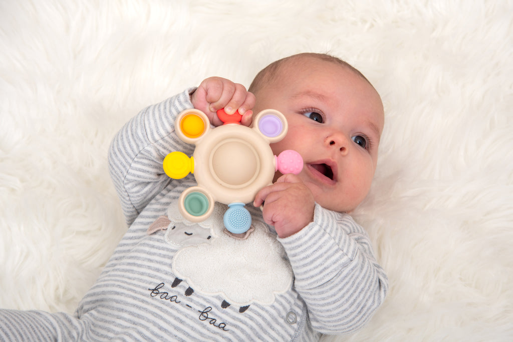 Beige silicone pop teether with rainbow rings and a textured grippy nub