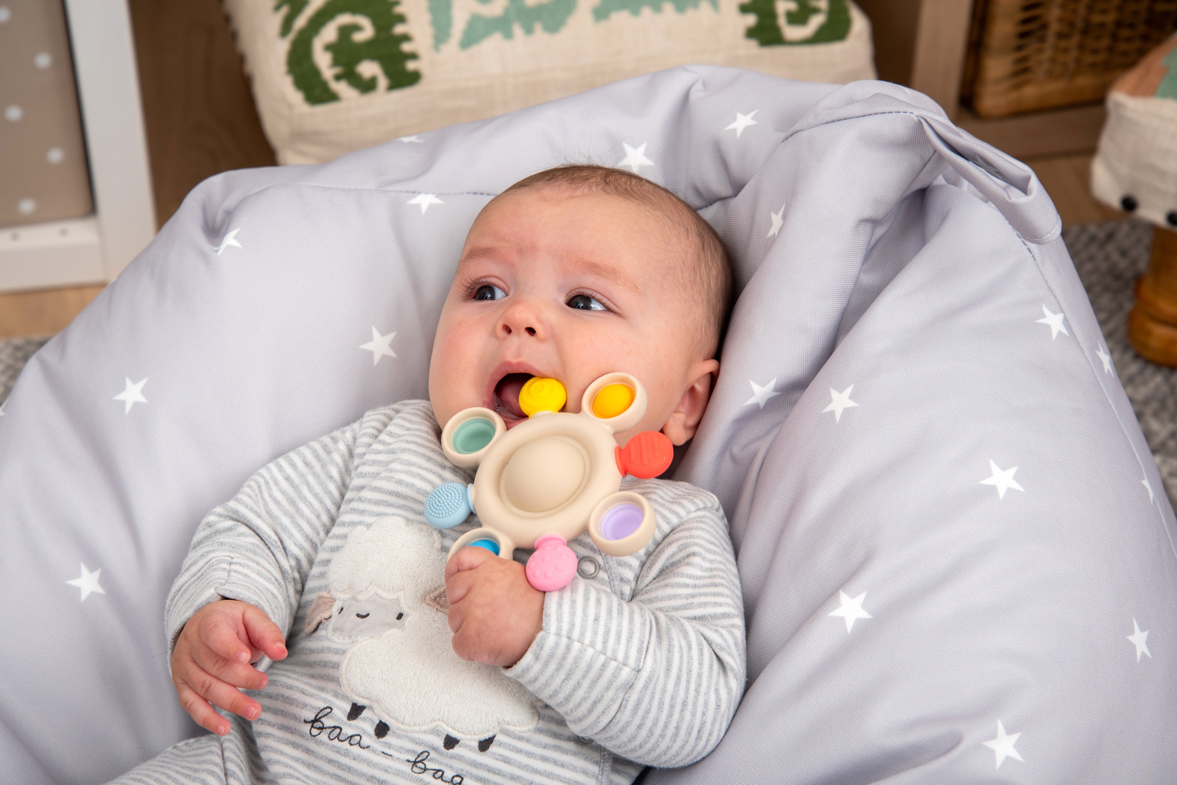 Rainbow silicone pop teether with beige center and multi-color pop rings