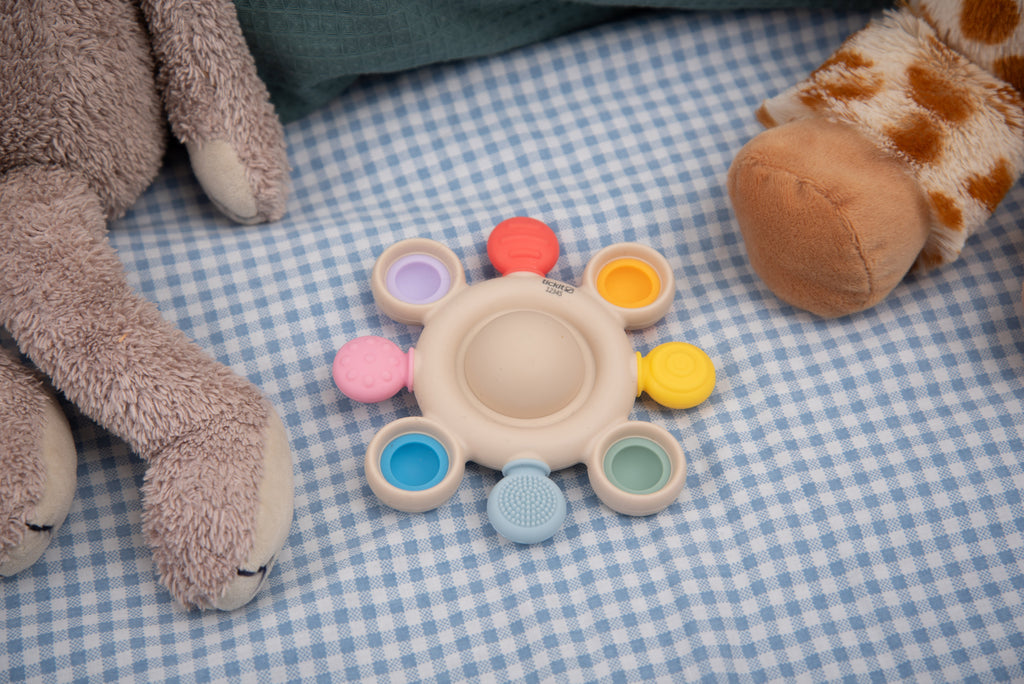 Pastel rainbow baby silicone pop teether with beige round base and pop rings
