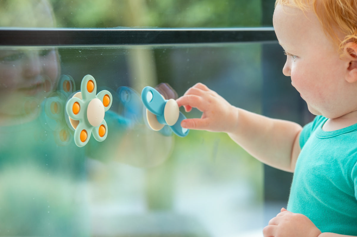 Propeller spinner toy held by a child, with blue handles and beige central disc