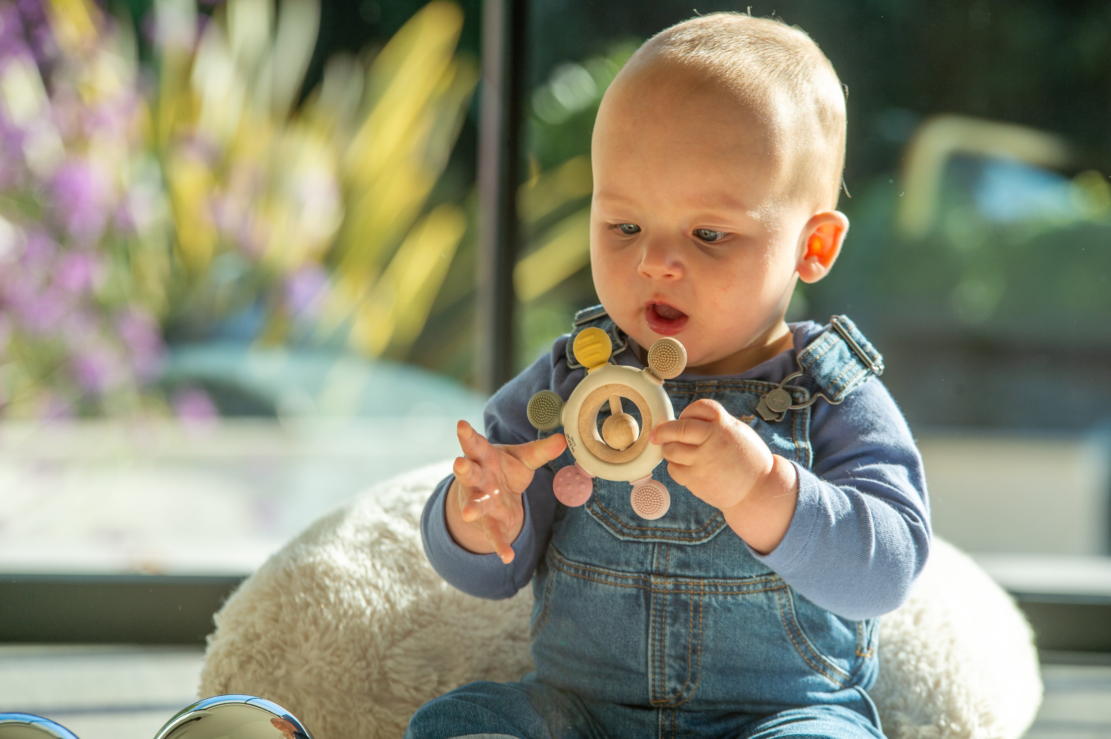 Baby holding wooden ring rattle teether with fabric textures and beads