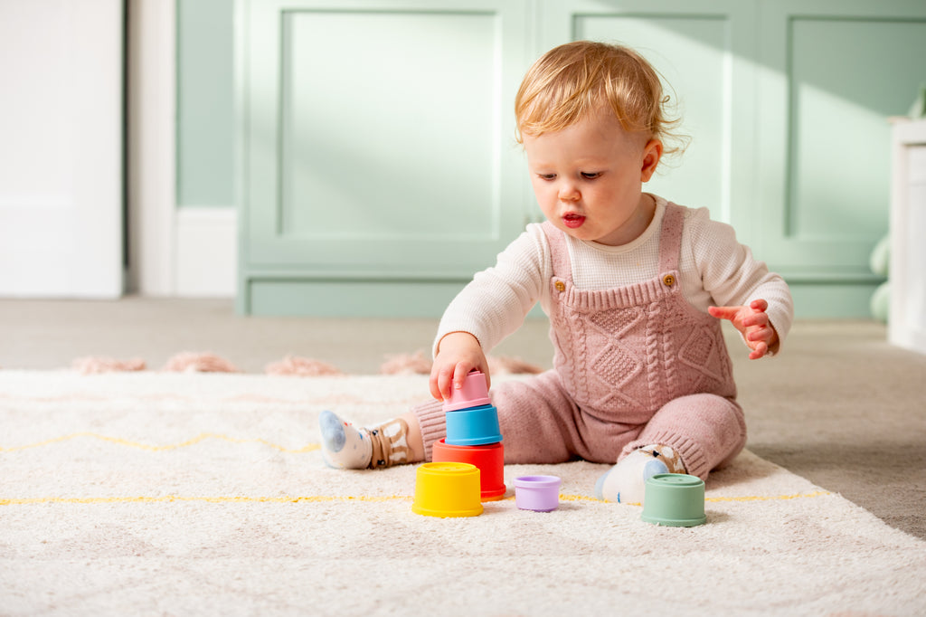 Silicone stacking cups with orange, yellow, teal, and purple pieces on carpet