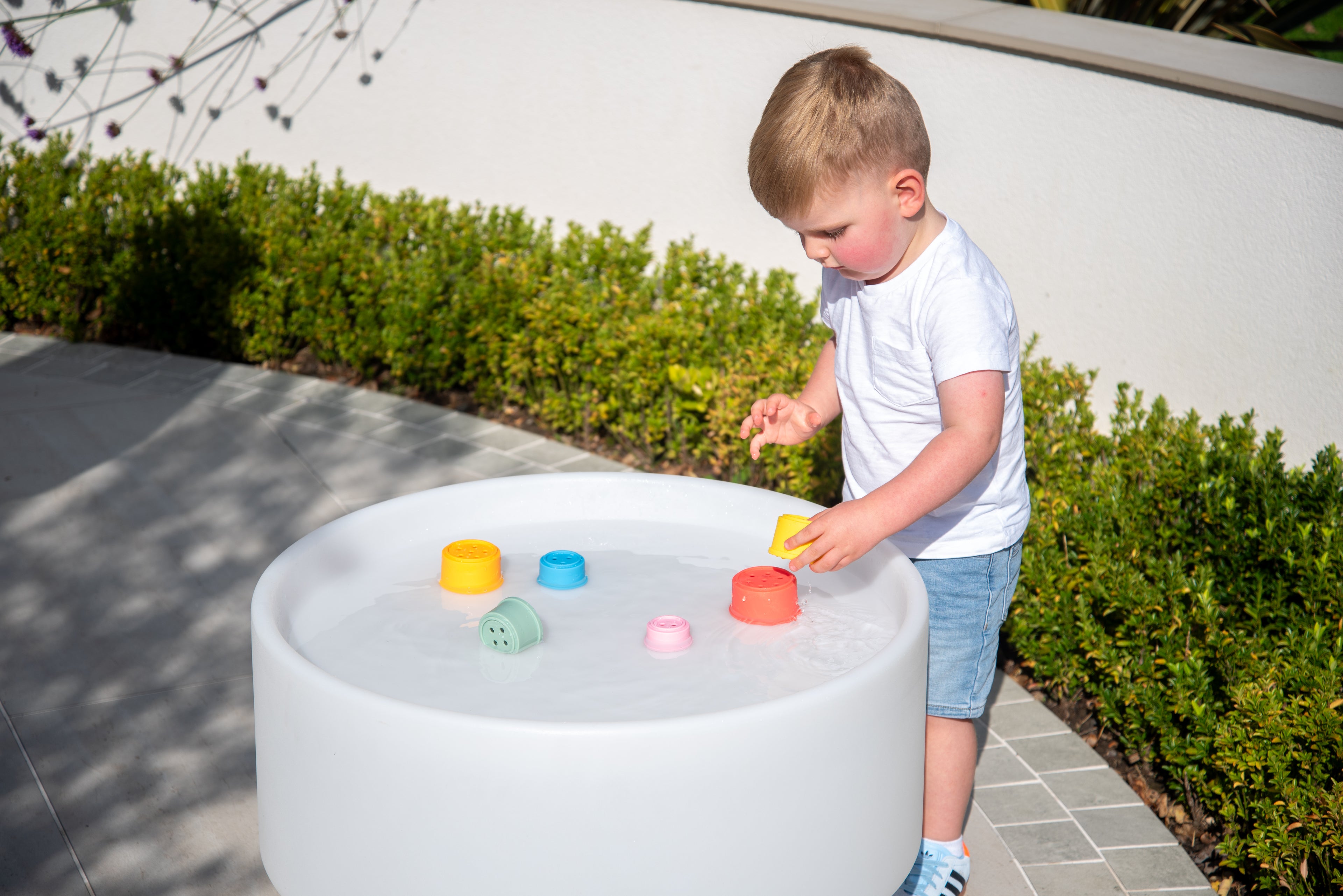 Rainbow silicone stacking cups in a round white play tub