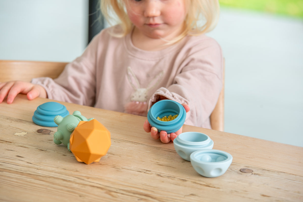 Blue and mint silicone sensory balls and stacking cups on wooden table