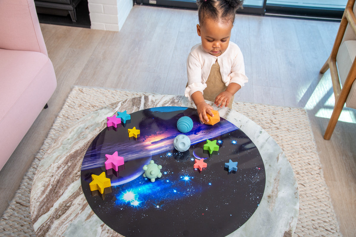 Sensory balls on round star play mat with blue, green, and pink star pieces