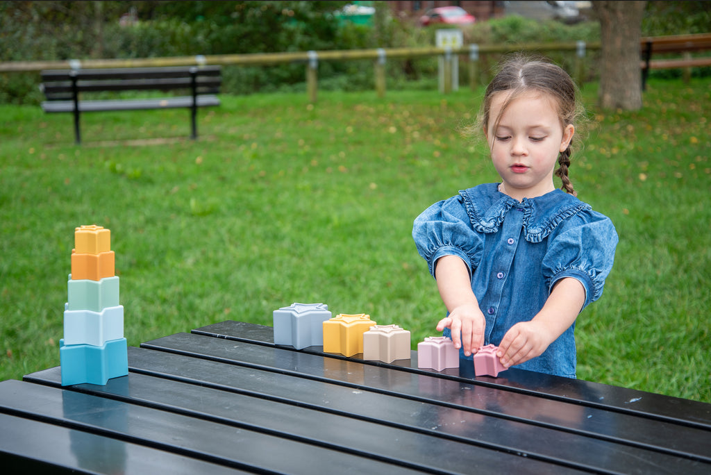 Stacking star cups scattered on a surface in blue, yellow, and pastel shades.