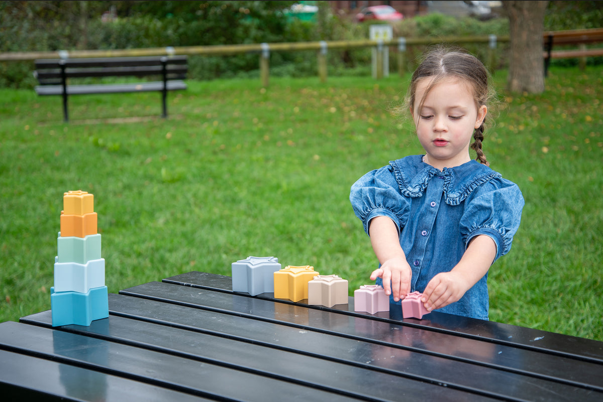 Stacking star cups scattered on a surface in blue, yellow, and pastel shades.