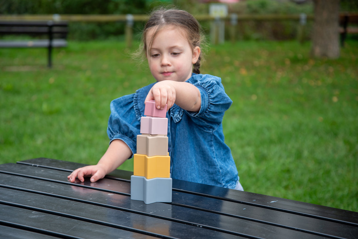 Pastel stacking star cups set held upright: pink, beige, and blue stacked layers.