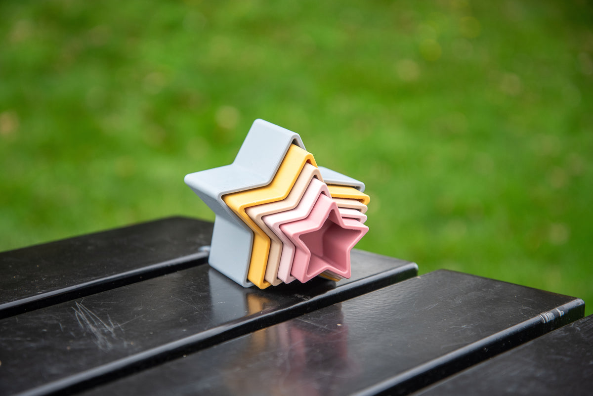 Nested star stacking cups in light blue base with pink, beige, and yellow star layers.