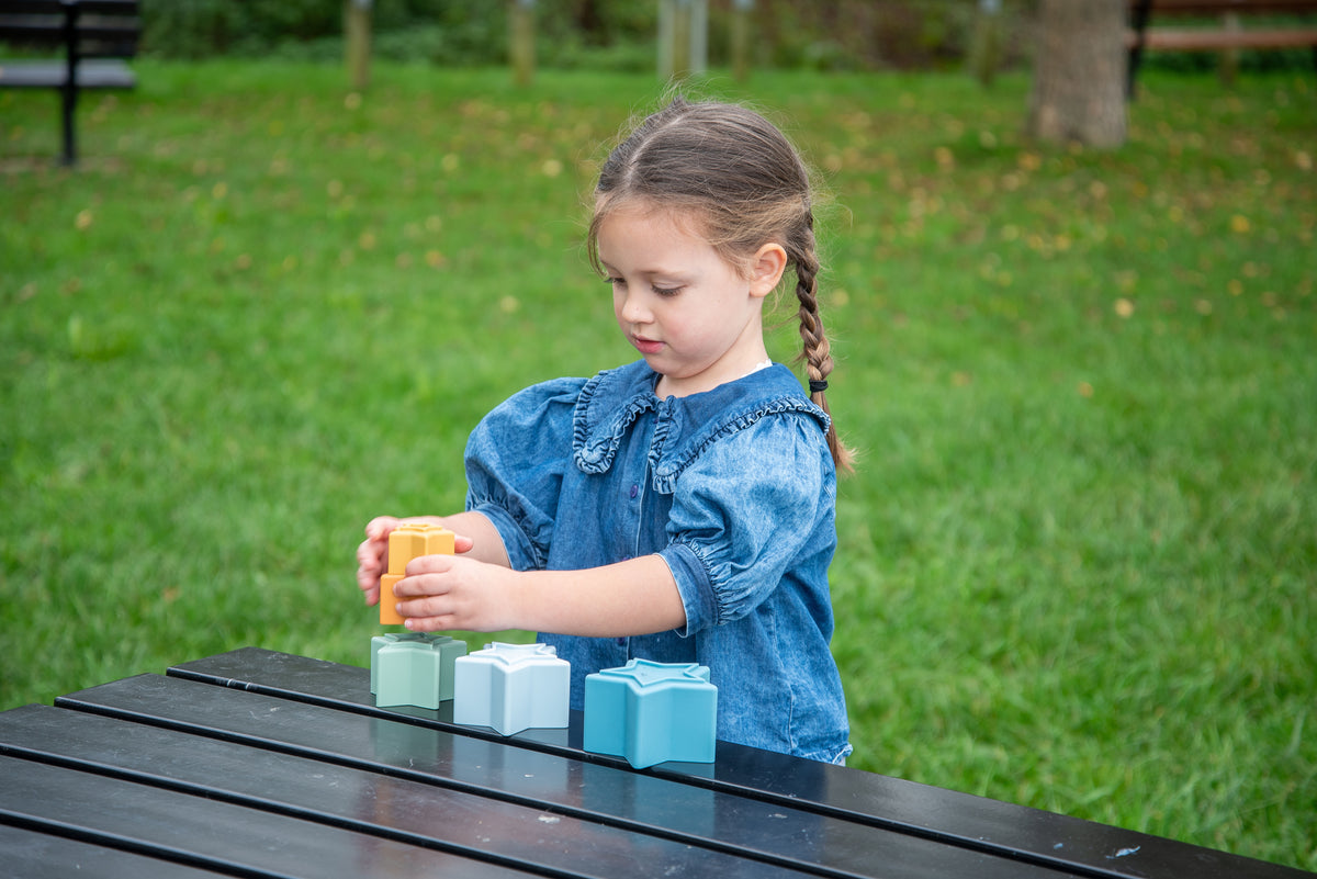 Child building with star stacking cups: blue blocks with orange top star