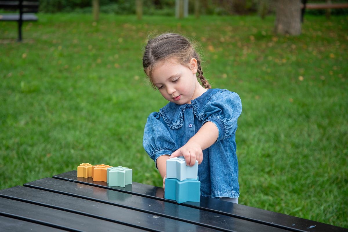 Child playing with star stacking cups: blue and orange star cups in hand