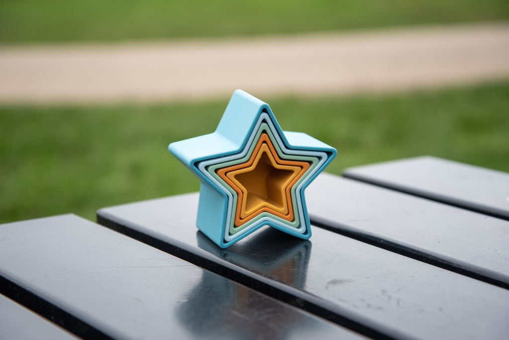 Star-shaped stacking cup with nested blue, orange, and light green layers