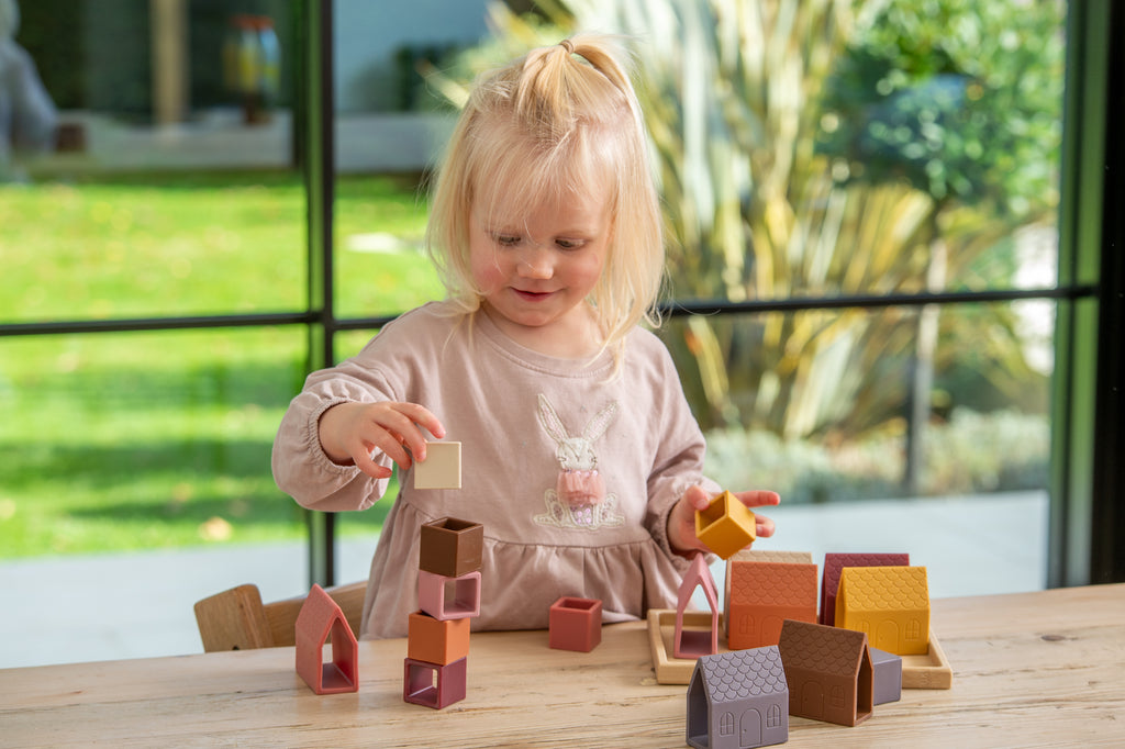 House-shaped silicone blocks on wooden tray with assorted earth-tone colors