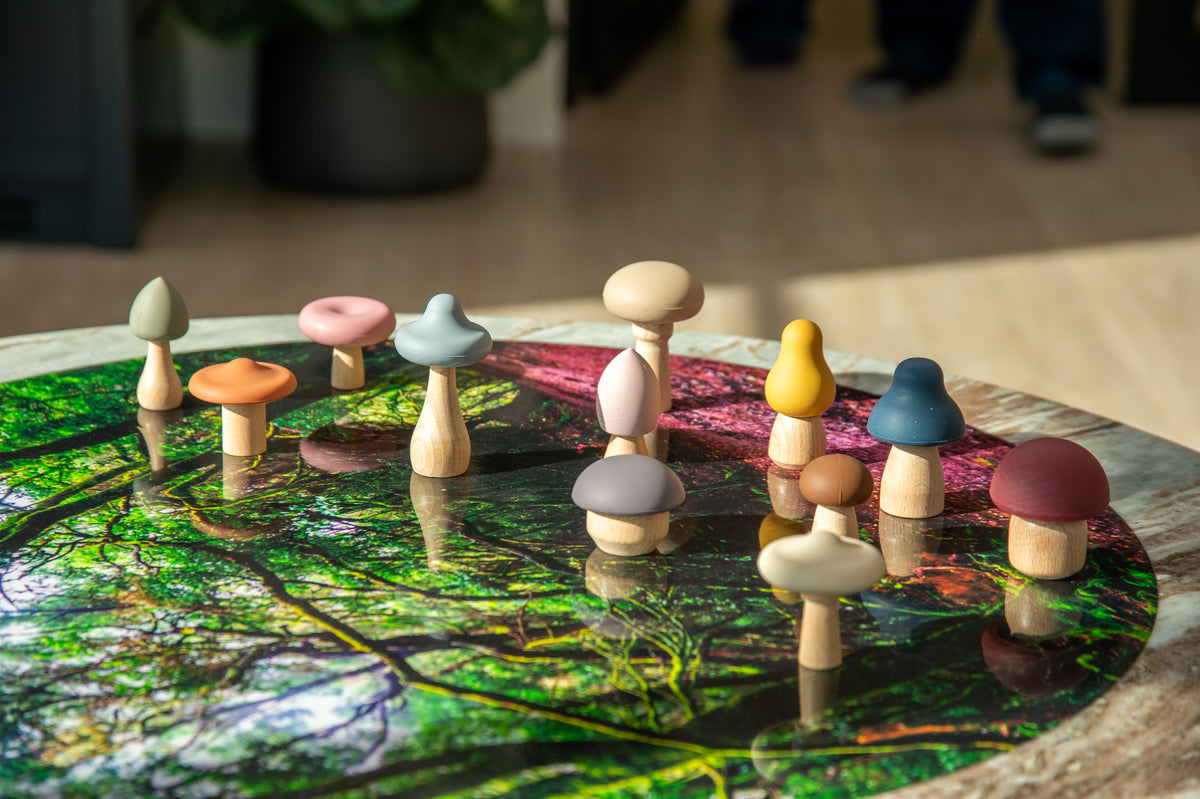 Wooden mushroom stacking pieces in earth tones standing on a round woodland mat