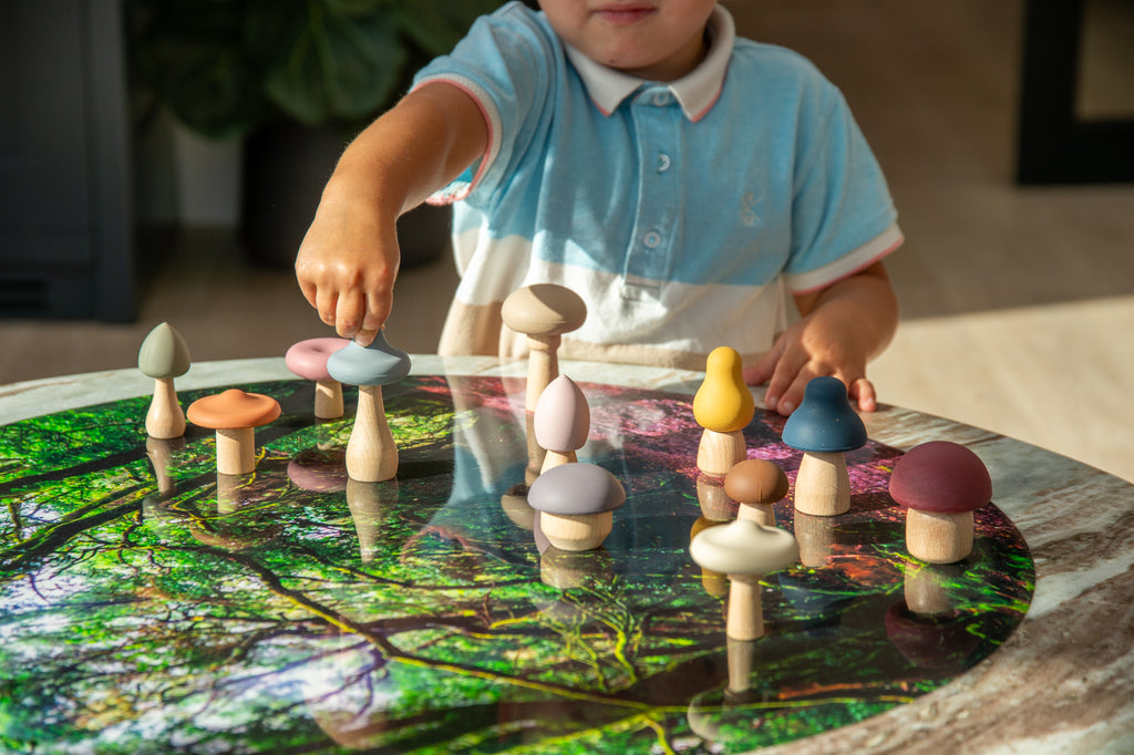 Child playing with colorful wooden mushroom stacking pieces on a woodland-pattern board