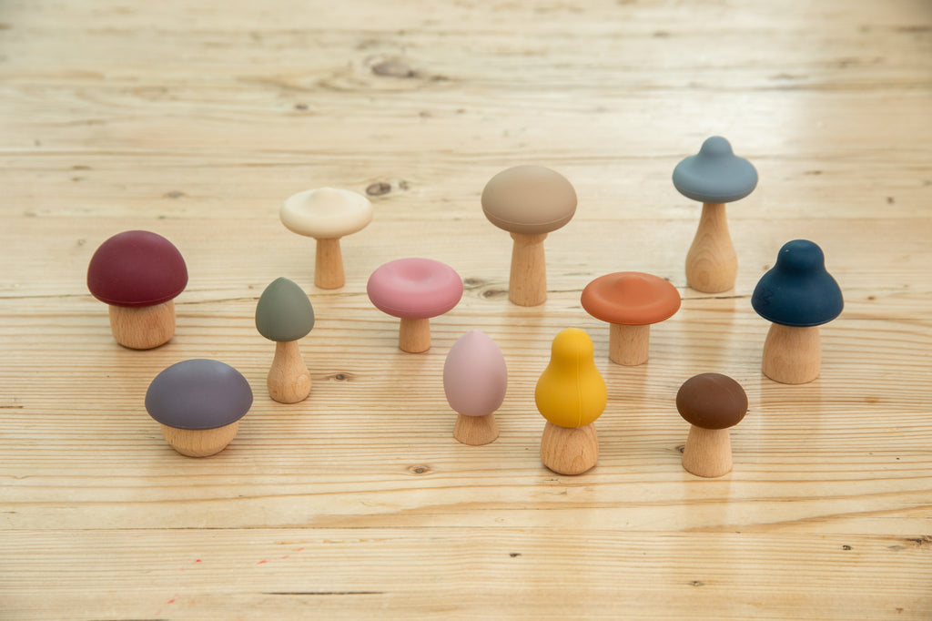 Set of wooden mushroom stacking pieces with assorted caps and beige, pink, and blue stems