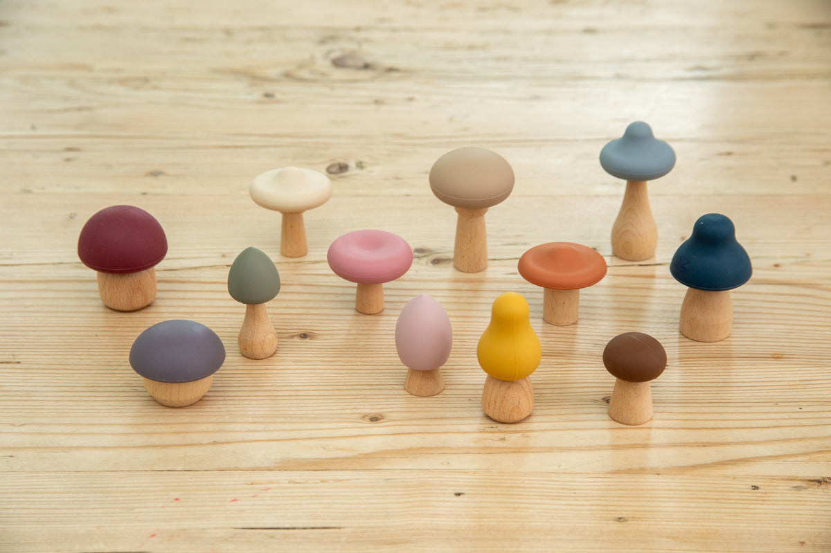 Set of wooden mushroom stacking pieces with assorted caps and beige, pink, and blue stems