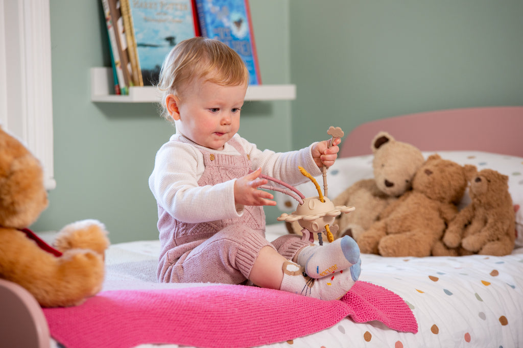Baby holding a zip pull earth activity toy with planet and dangling charms