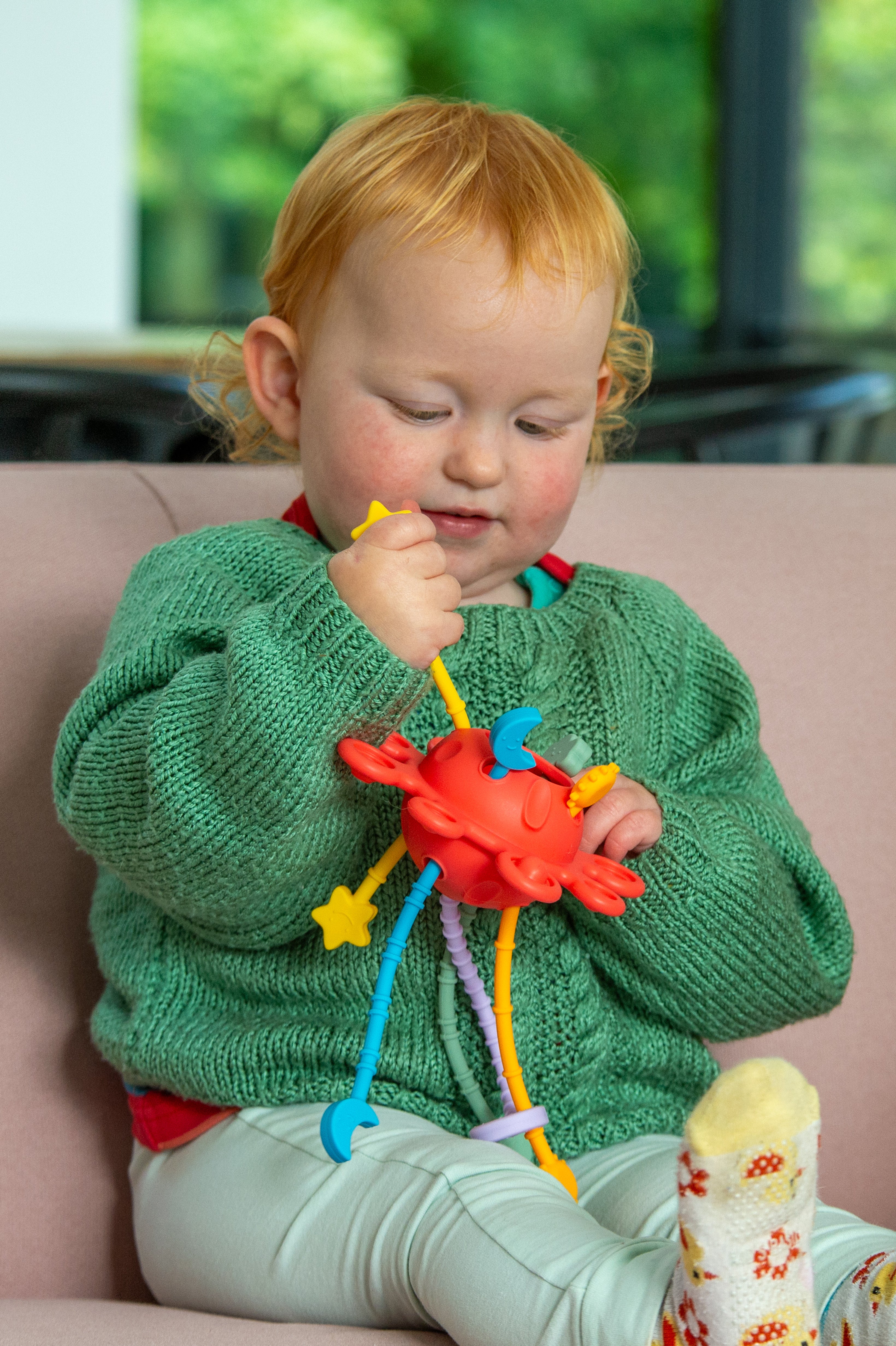 Toddler playing with Silisoft rainbow zip pull toy, bright zipper pulls and stars