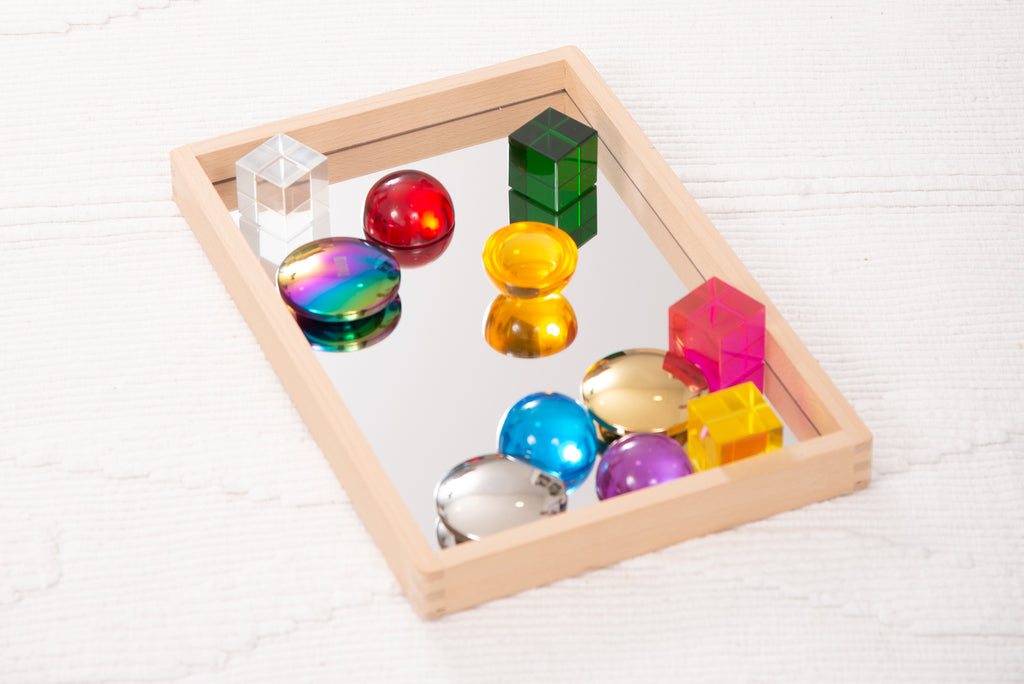Small wooden mirror tray with mirrored bottom holding colorful ball toys