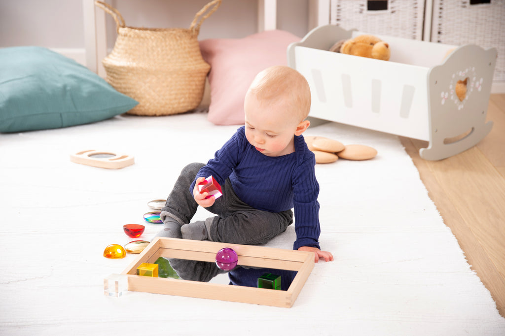 Small wooden mirror tray with mirrored bottom and colorful toy balls inside