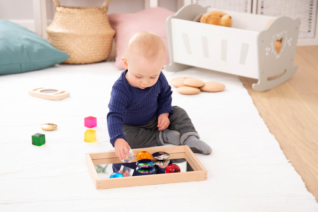 Small wooden mirror tray with mirrored insert and assorted colorful toy pieces